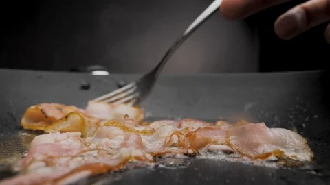 The bacon is fried in a pan. Video stock 117518399