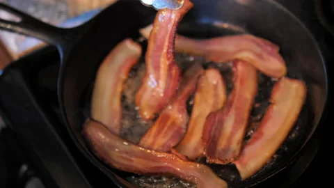 Bacon frying and turning crispy in cast iron skillet. Stock Footage 138473209