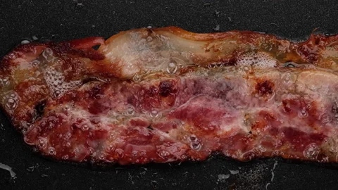 Bacon frying, macro. Bacon slices in frying pan, top view Video stock 160251607