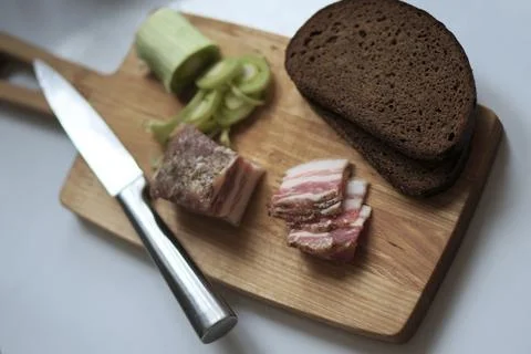 Bacon, leeks, black bread and a knife Stock Photos
