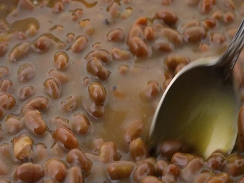 Bacon onion flavored baked beans being stirred with a spoon Stock Footage 75585291