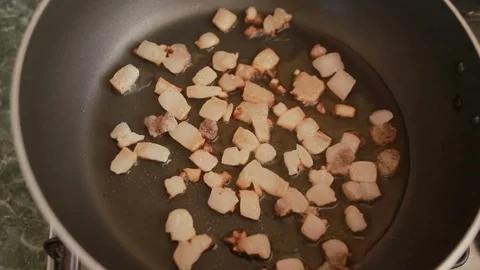 Bacon pieces on a hot frying pan are toasted Stock Footage 74139712