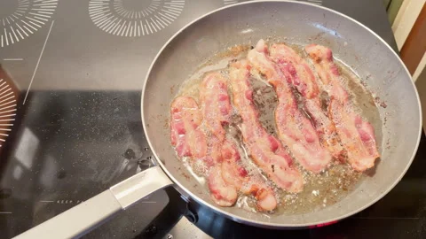 Bacon sizzles in a pan on induction stovetop 動画素材 344905823