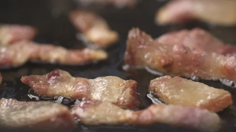 Bacon sizzling in a pan in slow motion, camera pans left to right Stock Footage 89936525