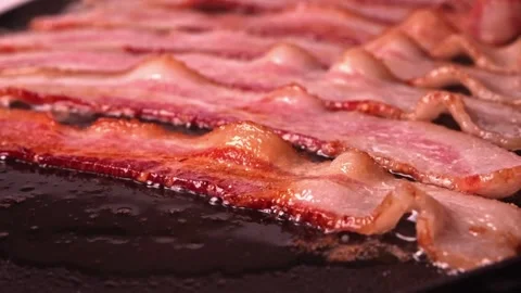 Bacon slices sizzle and bubble in frying pan. easy to cook bachelor breakfast. 스톡 동영상 334643041