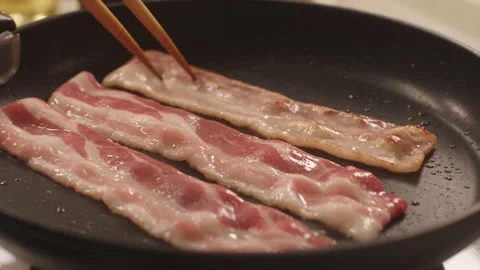 Bacon Strips Being Turned in a Pan with Cooking Utensil Video stock 347245673