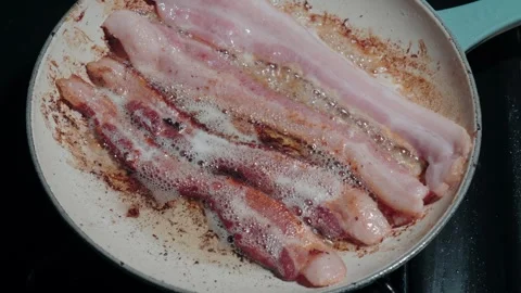 Bacon strips sizzling and frying in a hot skillet pan Vídeo Stock 344628317