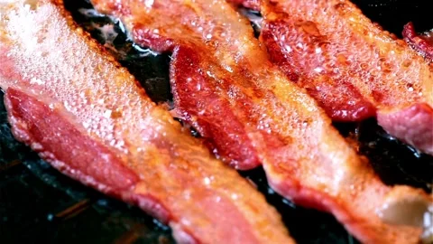 Bacon strips sizzling on a frying pan. Close up video of bacon being fried. 스톡 동영상 334641630