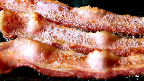 Bacon strips sizzling on a frying pan. Close up video of bacon being fried. 스톡 동영상 334641639