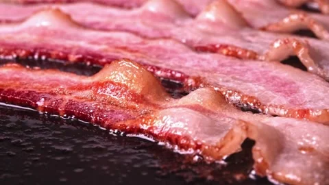 Bacon strips sizzling on a frying pan. Close up video of bacon being fried. 스톡 동영상 334641649