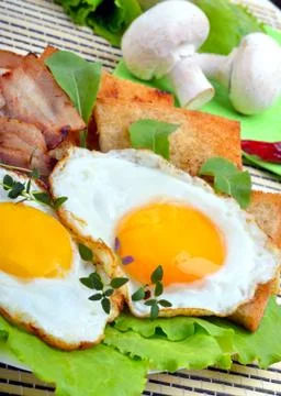 Bacon with sunny side up eggs served with toasts Stock Photos