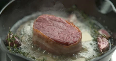 Bacon-wrapped beef tournedos, cooked in butter, garlic and thyme, in a deep fryi Stock Footage 199459250