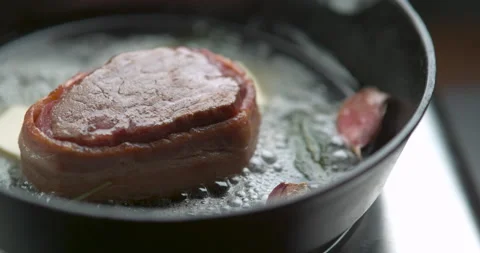 Bacon-wrapped beef tournedos, cooked in butter, garlic and thyme, in frying pan. Stock Footage 199461277