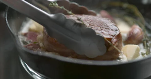 Bacon-wrapped beef tournedos, placed in a frying pan with tongs, cooked in butte Stock Footage 199457095