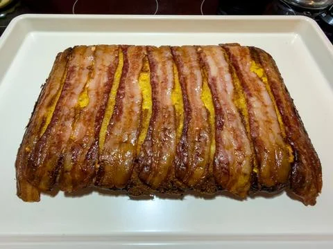 Bacon-Wrapped Cornbread Loaf on White Serving Platter Stock Photos