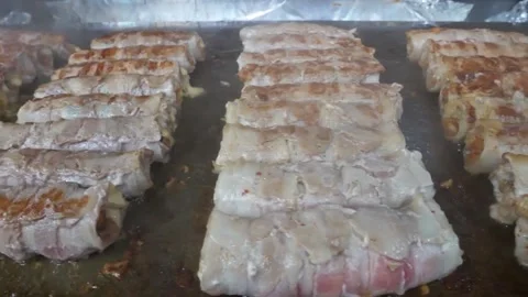 Bacon-Wrapped Meat Rolls Sizzling on a Flat Top Griddle 스톡 동영상 343588027
