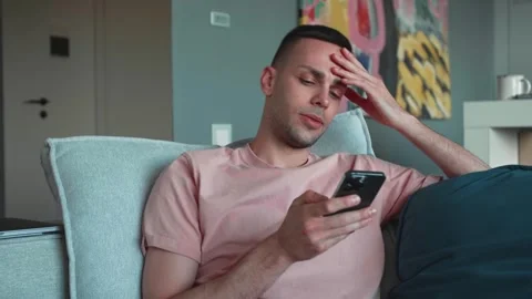 Bad news, device problem, app crash concept. Young man sit on sofa in living Stock Footage 241746919