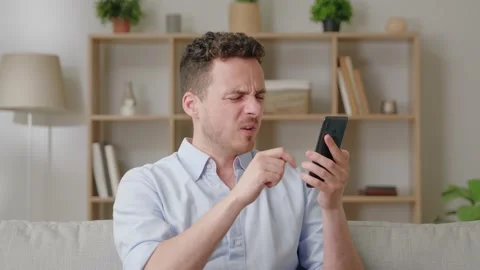 Bad sms news, device problem, app crash concept. Young man sit on sofa in living Stock Footage 169017286