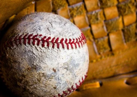 Badly damaged old baseball with texture of baseball glove closeup. Stock Photos