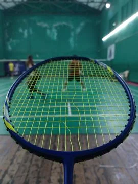 Badminton Racket head with broken strings with badminton court behind Stock Photos