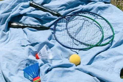 Badminton rackets and shuttlecocks on blue fabric outdoors Stock Photos