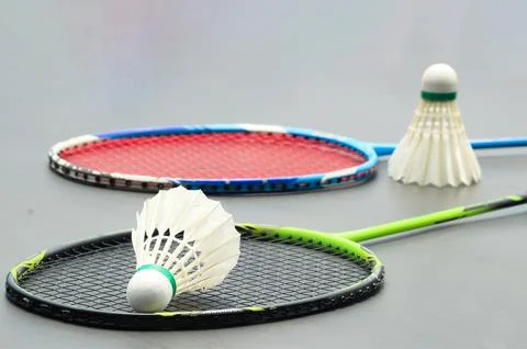 Badminton shuttlecocks with rackets on a dark background symbolizing the sp.. Stock Photos