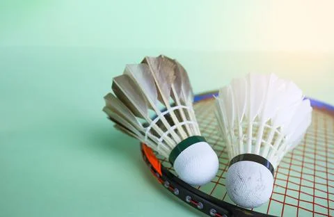 Badminton shuttlecocks with rackets on a green background symbolizing the s.. Stock Photos