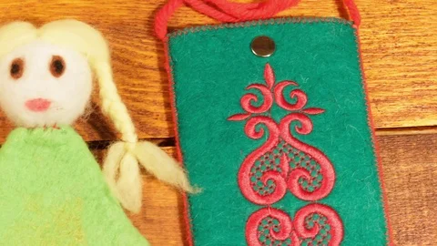 Bag and doll of felt wool on a wooden background Stock Footage 73287607