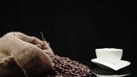 Bag full of coffee beans scattered on the table with a white cup Stock Footage 208767517