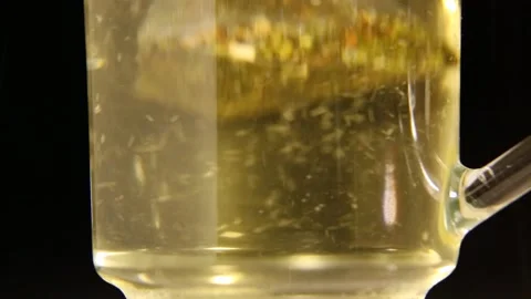 A bag of green tea in a transparent mug. Boiling water is poured into the mug. Stock Footage 168533377