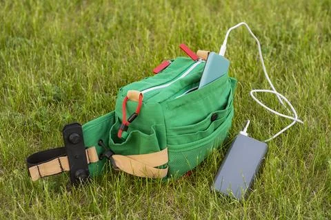 Bag with a smartphone is charged using a power bank. Portable charger in nature Stock Photos