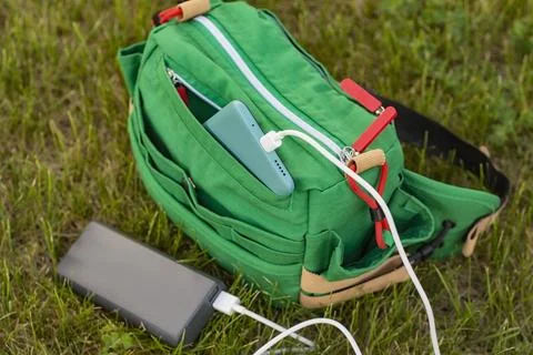 Bag with a smartphone is charged using a power bank. Portable charger in nature Stock Photos