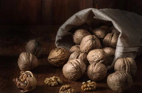 Bag with walnuts and kernels on a dark wooden background Stock Photos