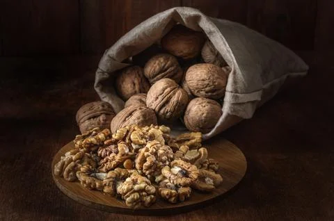 Bag with walnuts and kernels on a dark wooden background Stock Photos