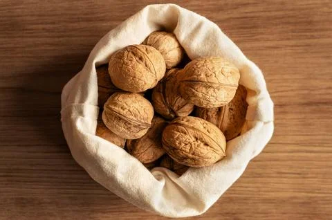 Bag of walnuts on wooden table. Stock Photos