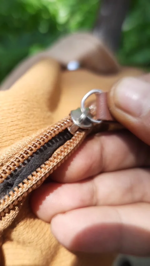 Bag zipper opening by hands, close-up vertical shot of brown textile accessor Stock Footage 342628044