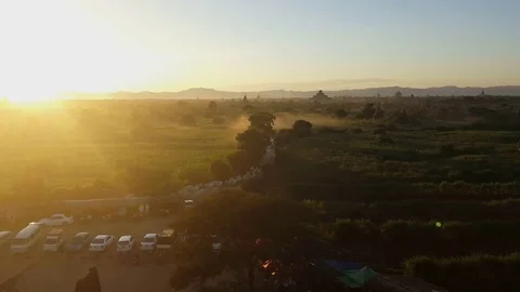 Bagan landscape at sunset, cattle walk on path, parked cars and tourist vans Stockbeeldmateriaal 78847784
