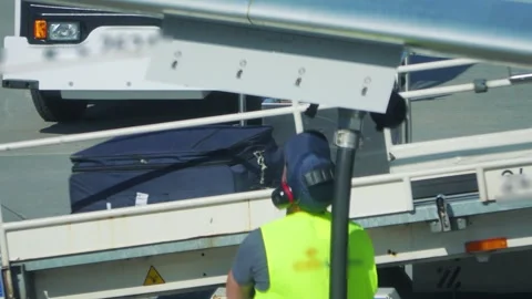 Baggage handler loading luggage onto an airport conveyor with focus and eff.. Stock Footage 293141447