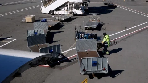 Baggage handler moves an empty luggage cart on an airport tarmac. Stock Footage 116043778