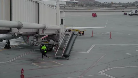 Baggage Handler in Neon Green Jacket Steps Off Airstairs onto Tarmac of Video stock 149381484