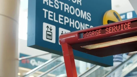 Baggage Services Scrolling Marquee Sign At Airport with Travelers in Background Stock Footage 124767324