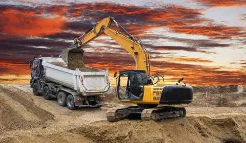 Bagger arbeitet auf einer Baustelle mit dramatischen Wolken Bagger arbeite... Stock Photos