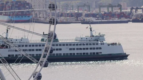 Bainbridge ferry headed out from seattle port with moving ferris wheel Stock Footage 83319974