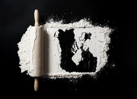 Bake background with free space for text. Rolling pins and flour on a black t Stock Photos