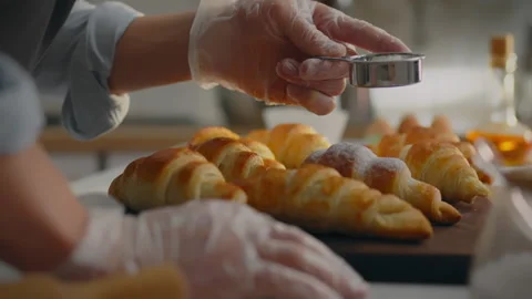 Bake. A baker dressed in comfortable work clothes sprinkles powdered sugar o Stock Footage 270383327