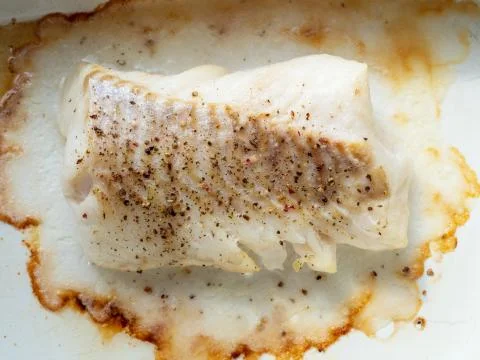 Baked and peppered cod in white ceramic pan Stock Photos