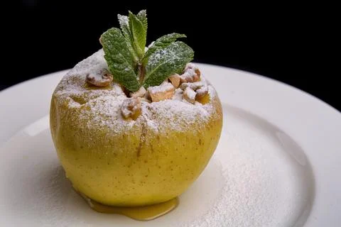 Baked Apple with Nuts, Mint, and Powdered Sugar on White Plate Stock Photos