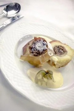 Baked apples stuffed with a mixture of nuts and raisins, on vanilla sauce Stock Photos