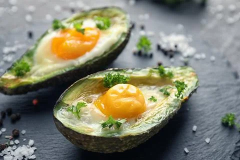 Baked avocado with eggs on table Stock Photos