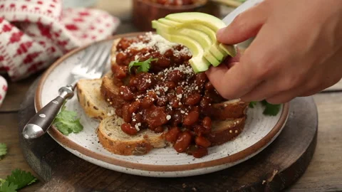 Baked beans on toast with cilantro, adding avocado Stock Footage 242534023
